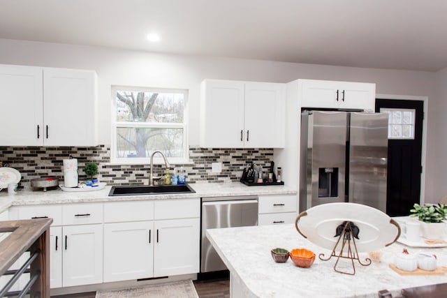 kitchen with decorative backsplash, appliances with stainless steel finishes, a sink, and white cabinetry