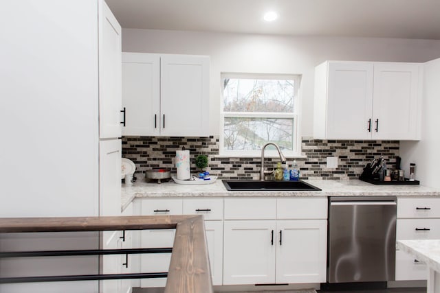 kitchen with backsplash, dishwasher, white cabinets, and a sink
