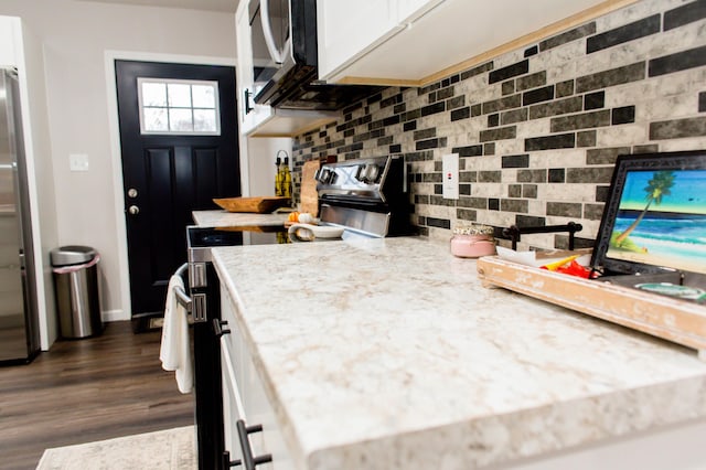 kitchen featuring white cabinets, tasteful backsplash, appliances with stainless steel finishes, and dark wood-style flooring