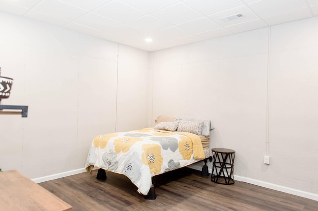 bedroom with baseboards, visible vents, wood finished floors, and a drop ceiling
