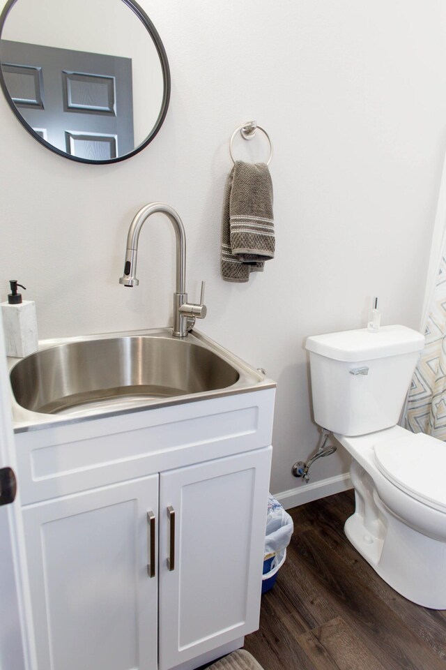 bathroom with baseboards, wood finished floors, toilet, and vanity