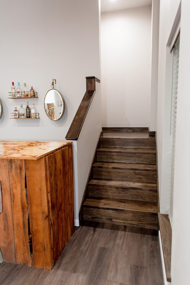 staircase featuring a dry bar and wood finished floors