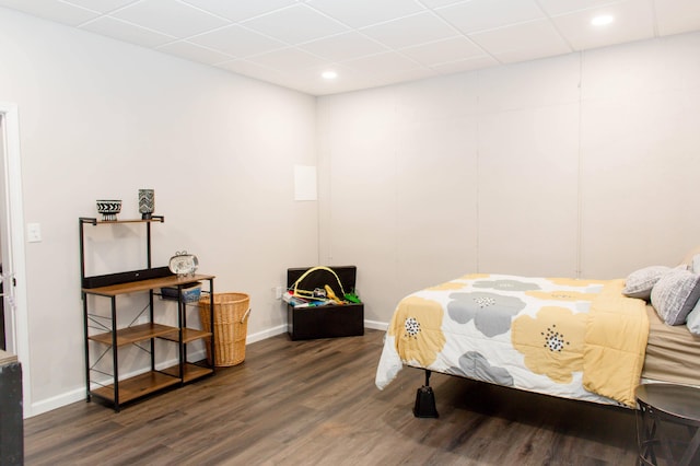 bedroom featuring wood finished floors, a drop ceiling, and baseboards