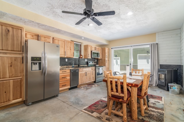 kitchen with ceiling fan, decorative backsplash, stainless steel appliances, light brown cabinetry, and a textured ceiling