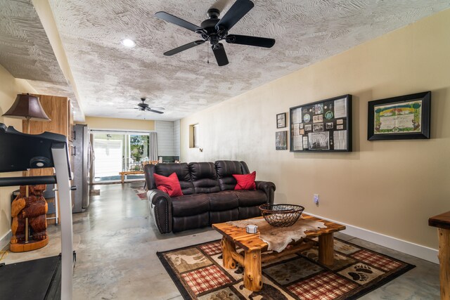 living room with ceiling fan, a textured ceiling, and concrete flooring