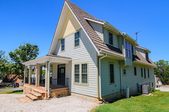 view of front facade featuring central AC, a porch, and a front yard