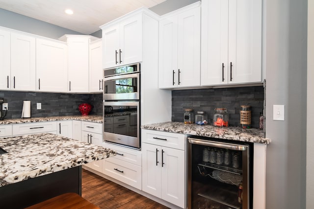 kitchen featuring dark hardwood / wood-style floors, white cabinets, double oven, wine cooler, and backsplash