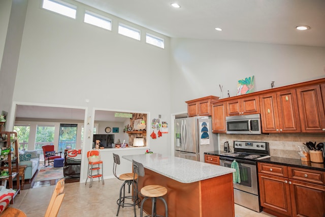 kitchen with stainless steel appliances, plenty of natural light, high vaulted ceiling, and a center island