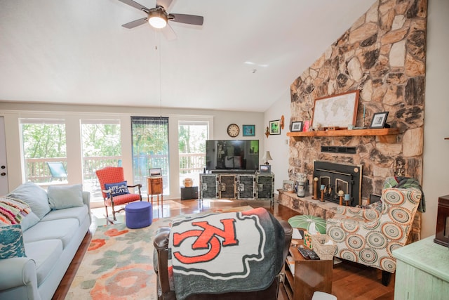 living room with ceiling fan, lofted ceiling, hardwood / wood-style flooring, and a stone fireplace