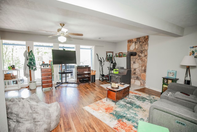 living room with ceiling fan, hardwood / wood-style floors, a textured ceiling, and a wood stove