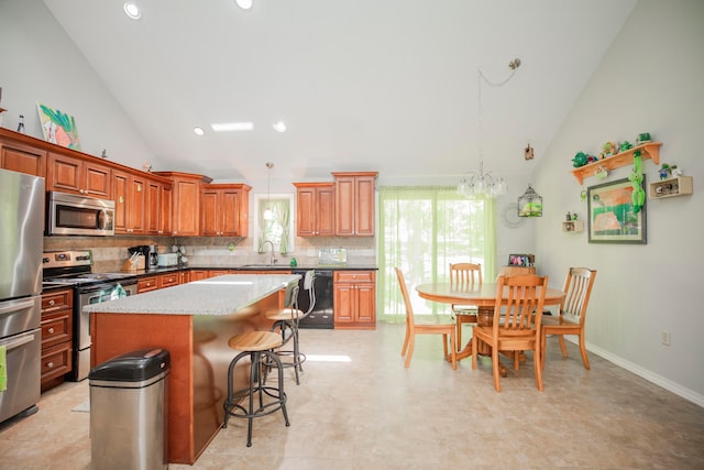 kitchen featuring backsplash, a kitchen island, sink, stainless steel appliances, and hanging light fixtures