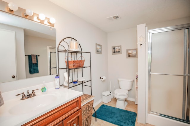 bathroom with tile patterned flooring, a shower with door, vanity, and toilet