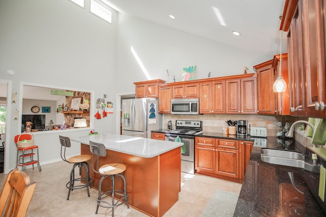 kitchen featuring appliances with stainless steel finishes, sink, dark stone countertops, and a center island