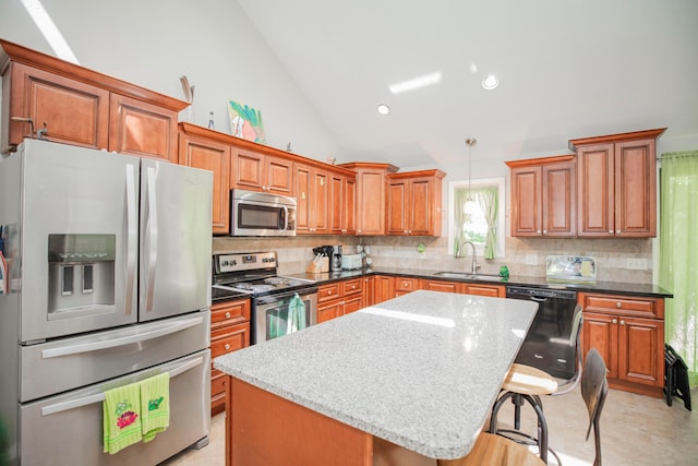 kitchen featuring sink, a kitchen island, decorative light fixtures, appliances with stainless steel finishes, and a breakfast bar