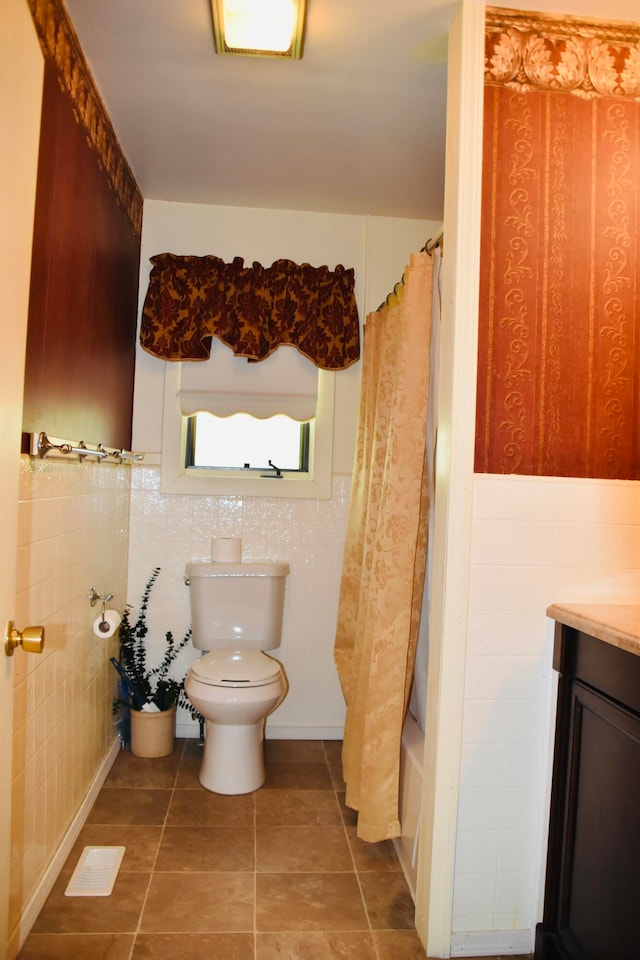 full bathroom with tile walls, tile patterned floors, vanity, toilet, and shower / bath combo with shower curtain