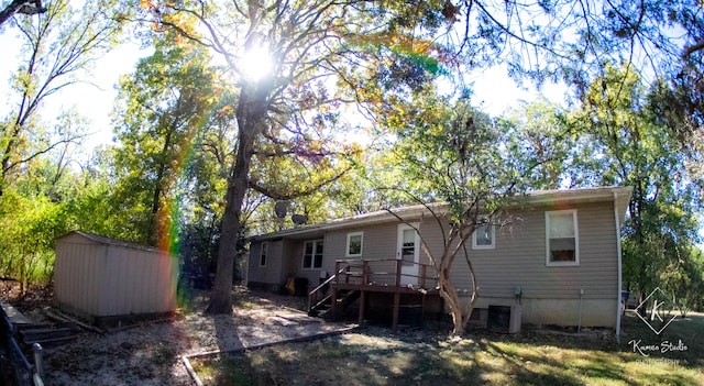 back of property with a deck, central air condition unit, and a storage shed