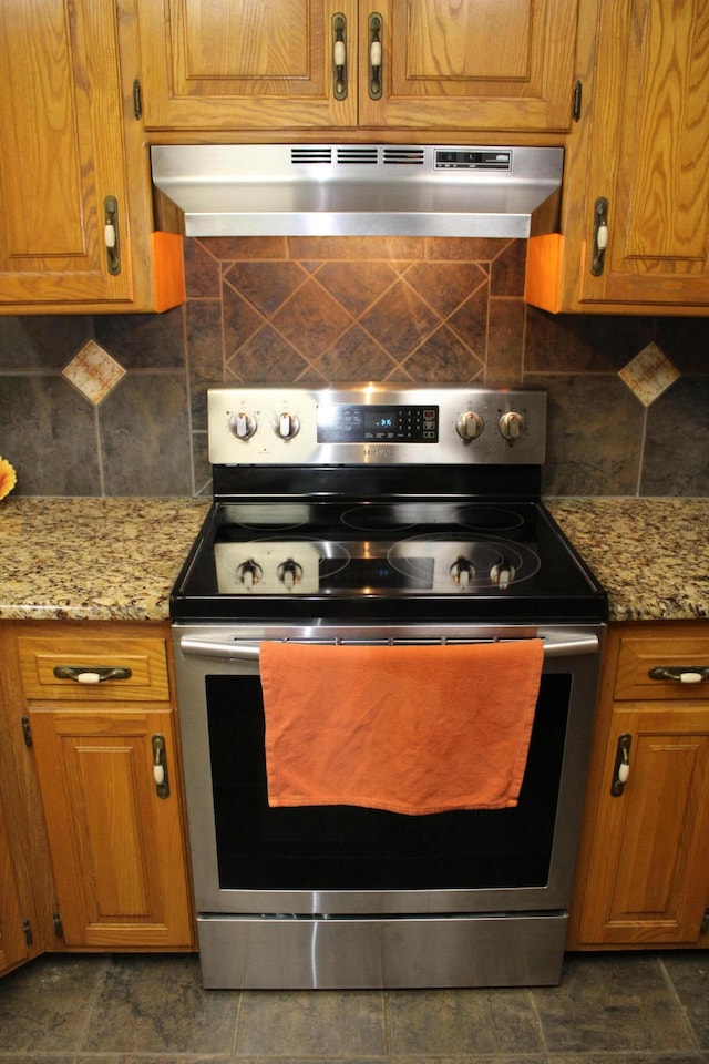 kitchen with wall chimney exhaust hood, stainless steel electric range oven, backsplash, and light stone countertops