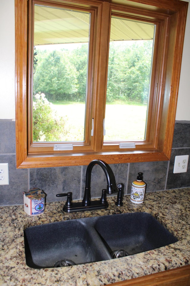 details featuring light stone counters, sink, and backsplash