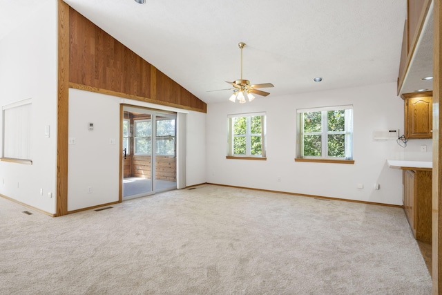 unfurnished living room with light carpet, high vaulted ceiling, and ceiling fan