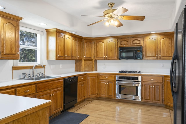 kitchen with black appliances, ceiling fan, sink, and light hardwood / wood-style flooring