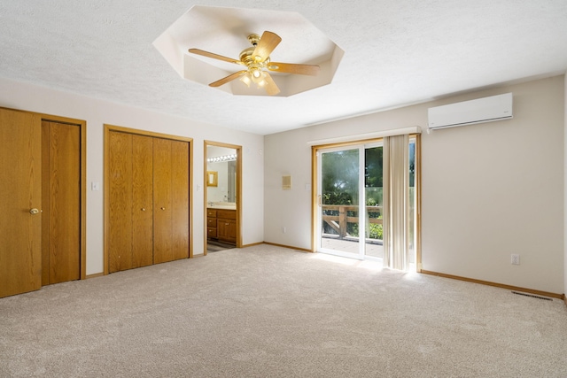 unfurnished bedroom featuring ceiling fan, access to outside, a wall mounted AC, connected bathroom, and a textured ceiling