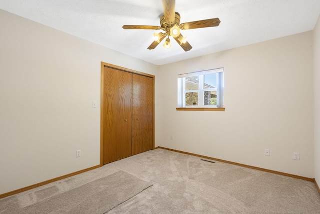 unfurnished bedroom with a closet, light colored carpet, and ceiling fan