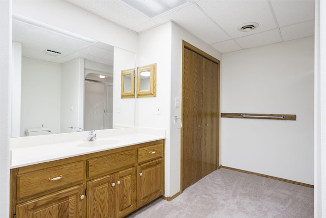 bathroom with vanity, a drop ceiling, toilet, and a shower with door