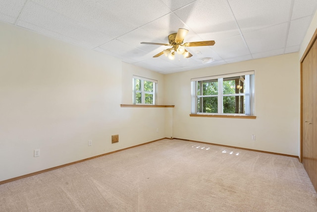 carpeted empty room featuring ceiling fan and a paneled ceiling