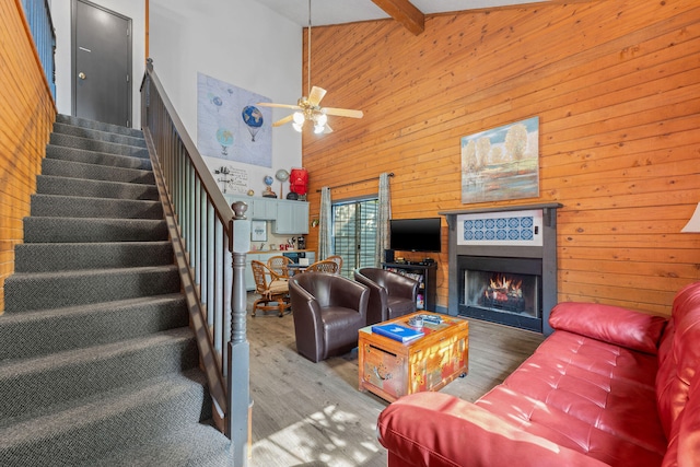 living room with beamed ceiling, a tiled fireplace, ceiling fan, high vaulted ceiling, and hardwood / wood-style flooring