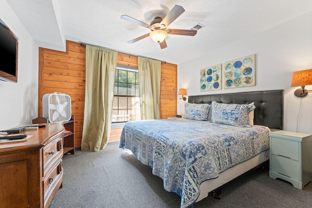 carpeted bedroom with a textured ceiling, wooden walls, and ceiling fan