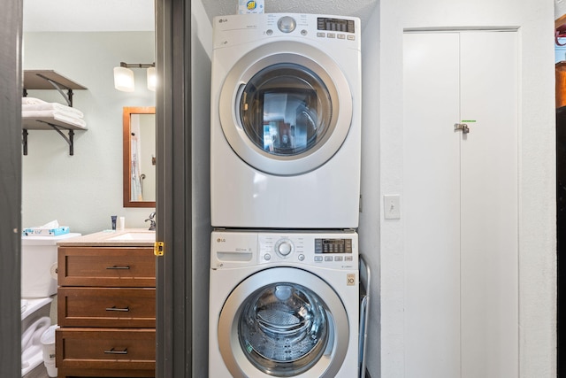 laundry area featuring stacked washer and clothes dryer and sink