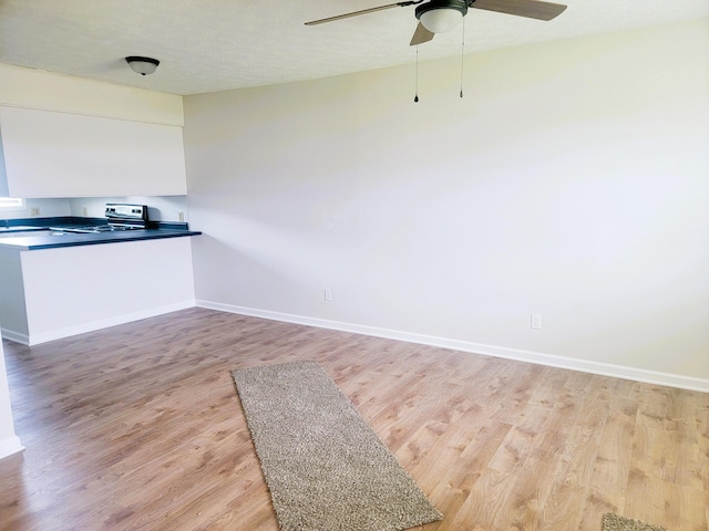 kitchen featuring ceiling fan, light hardwood / wood-style floors, stainless steel range oven, and a textured ceiling