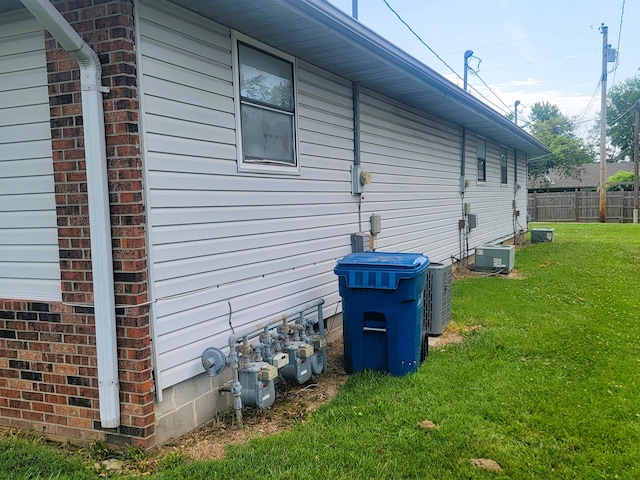 view of side of property with central air condition unit and a lawn