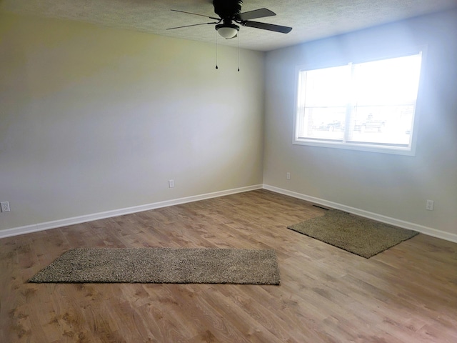 empty room featuring ceiling fan, a textured ceiling, and light hardwood / wood-style floors