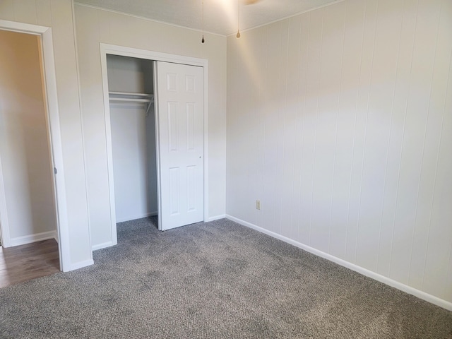 unfurnished bedroom with a closet and dark colored carpet