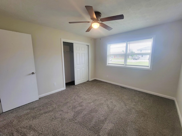 unfurnished bedroom with dark colored carpet, ceiling fan, a closet, and a textured ceiling