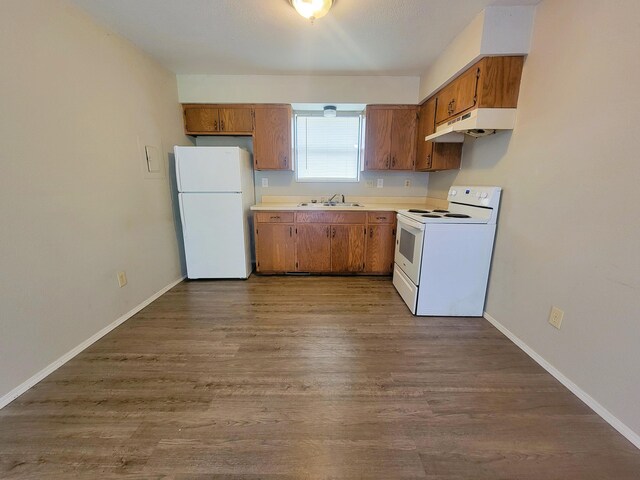 kitchen with hardwood / wood-style flooring, white appliances, and sink