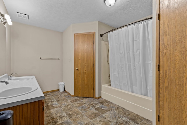 bathroom featuring shower / tub combo with curtain, vanity, and a textured ceiling