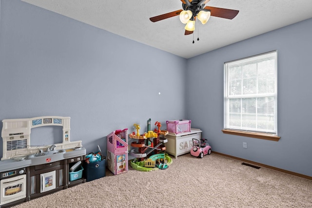 recreation room with a textured ceiling, ceiling fan, and carpet flooring