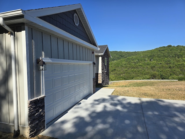 500 Timber Wolf Rd, Hollister, MO 65672 - view of side of home featuring a view of trees, stone siding, board and batten siding, and a garage