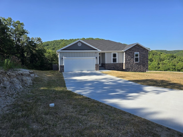 500 Timber Wolf Rd, Hollister, MO 65672 - view of front facade with board and batten siding, driveway, stone siding, a front lawn, and an attached garage