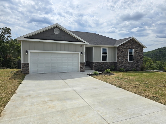 500 Timber Wolf Rd, Hollister, MO 65672 - view of front of home featuring a front lawn, a garage, driveway, stone siding, and board and batten siding