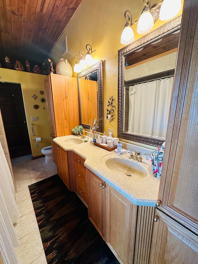 bathroom with vanity, toilet, wooden ceiling, tile patterned floors, and vaulted ceiling