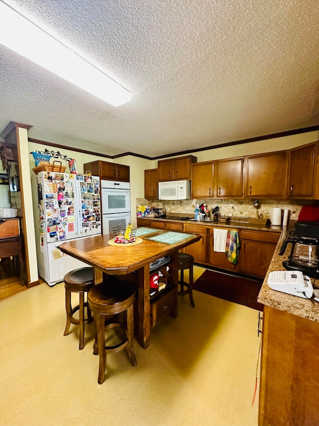 kitchen with crown molding, decorative backsplash, white appliances, and a textured ceiling