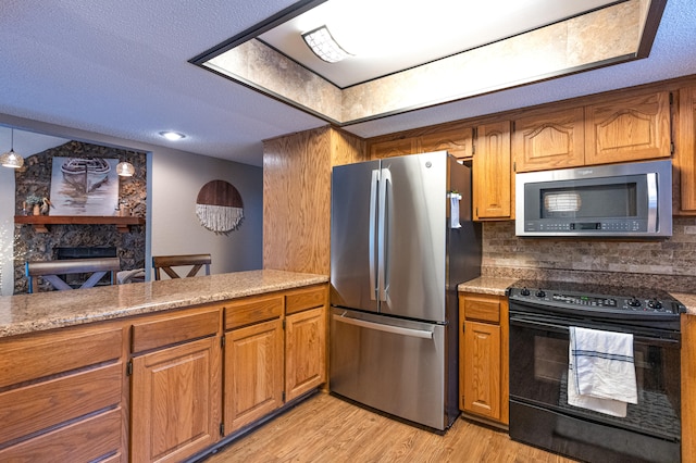 kitchen with light hardwood / wood-style floors, decorative backsplash, stainless steel appliances, and a textured ceiling