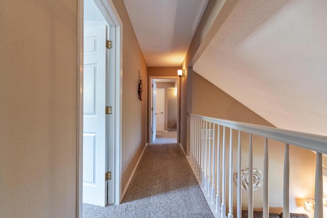 hall with light colored carpet and a textured ceiling