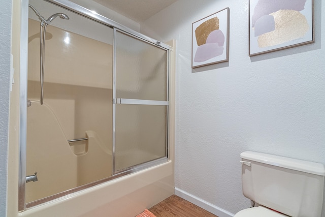 bathroom with bath / shower combo with glass door, hardwood / wood-style floors, and toilet