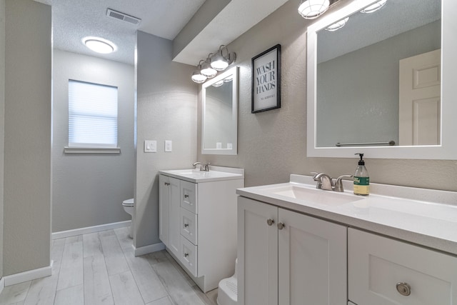 bathroom featuring hardwood / wood-style floors, toilet, vanity, and a textured ceiling