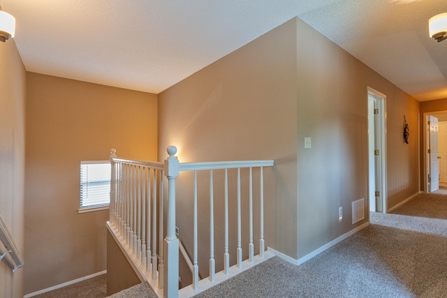 stairs with a textured ceiling and carpet flooring