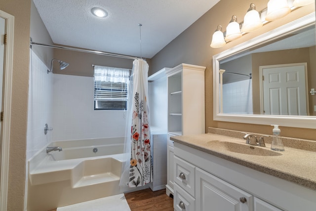 bathroom with vanity, shower / bath combo with shower curtain, hardwood / wood-style floors, and a textured ceiling